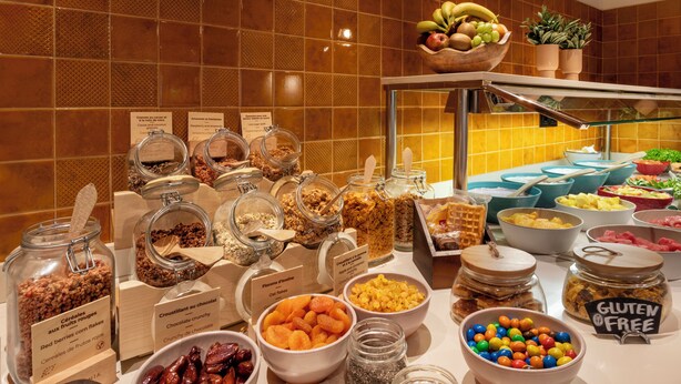 A buffet with various food options including fruits, nuts, and gluten-free selections.