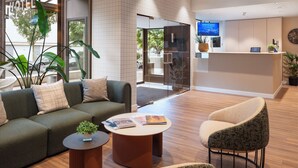 A modern hotel lobby with a reception desk, a sofa, a coffee table, and a chair.