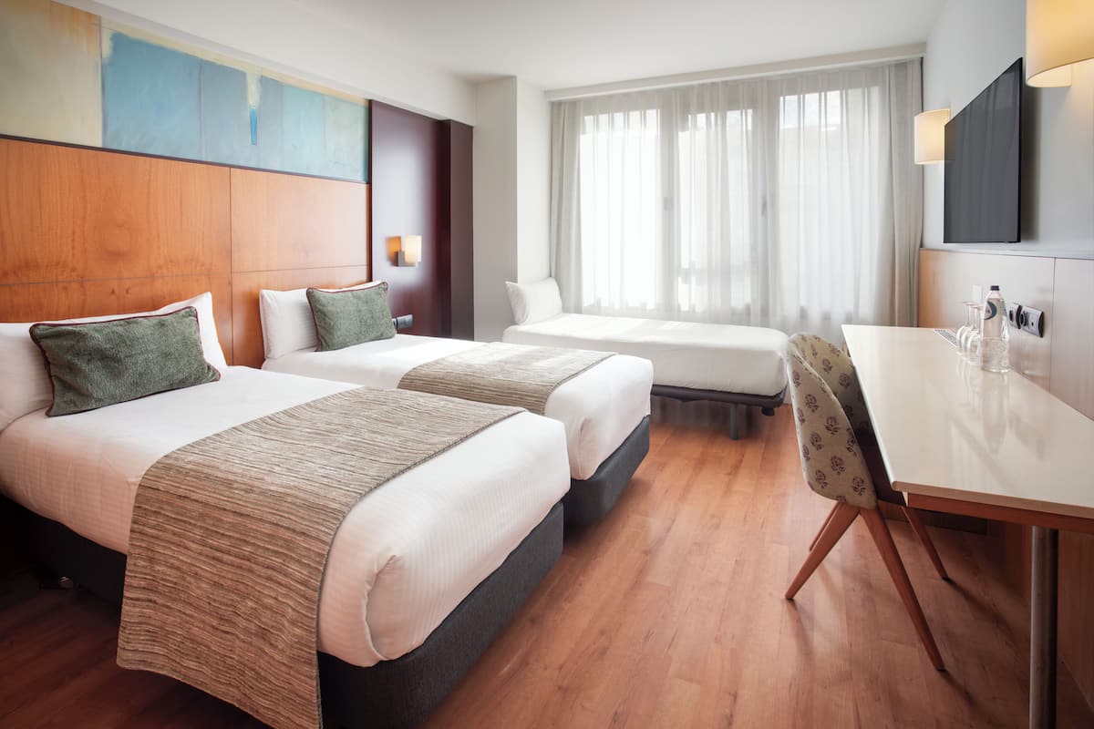 Una habitación de hotel con dos camas, un escritorio y televisión.