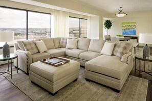 A modern living room with a sectional sofa, a coffee table, and a view of the city.