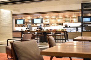A modern restaurant with a bar area, seating, and a kitchen visible in the background.