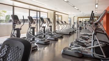 A gym with treadmills, elliptical machines, and a weight bench.