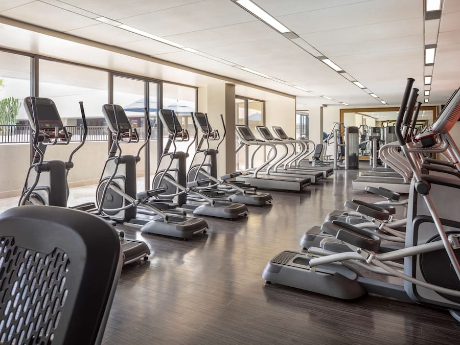 A gym with treadmills, elliptical machines, and a weight bench.