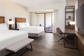 A hotel room with two beds, a desk, a chair, and a TV.