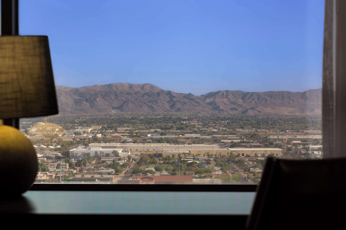 A view from a window overlooking a cityscape with mountains in the background.