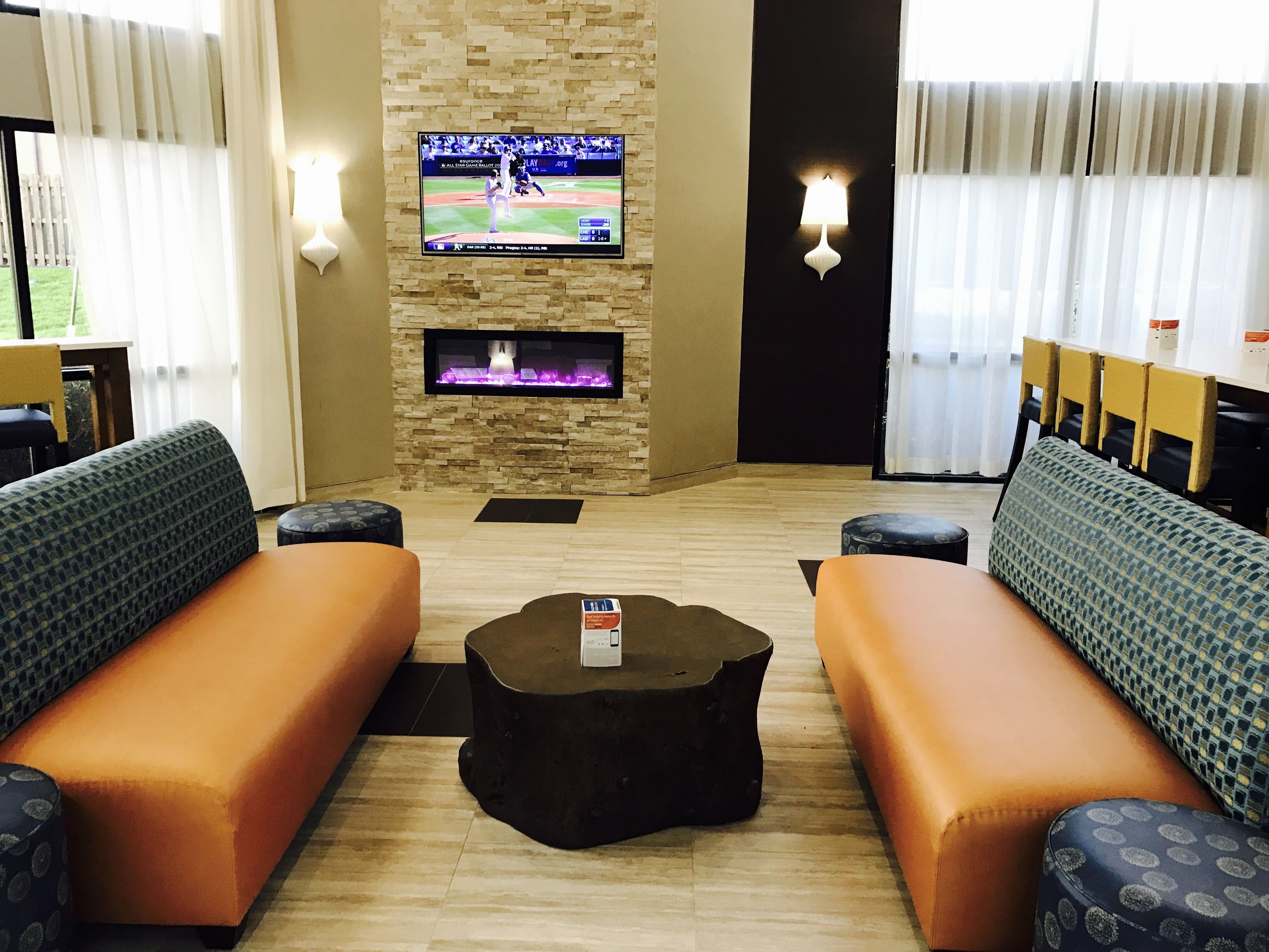 Una sala de estar moderna con chimenea, dos sofás, una mesa de centro y un televisor de pantalla plana montado en una pared de piedra.