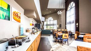 Zona pranzo moderna con servizio a buffet, mobili in legno e diverse opzioni di posti a sedere, tra cui tavoli e sedie.