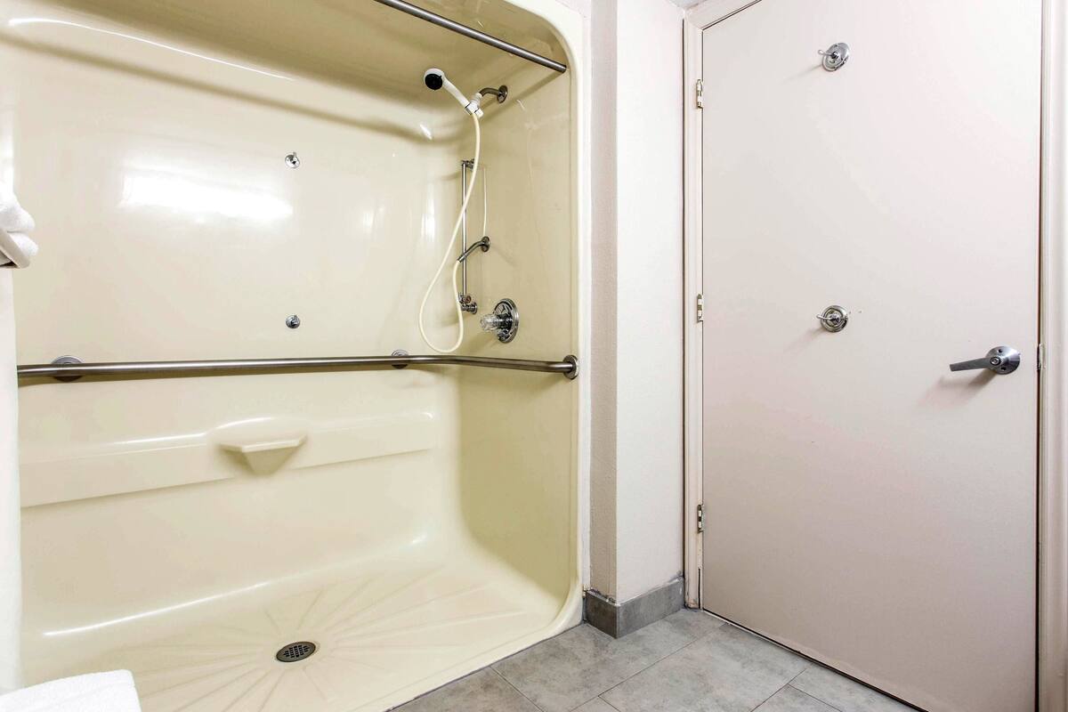A bathroom with a bathtub, a shower, and a door.