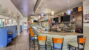 A bar area with seating, a counter, and a television. - Clarion Inn Salt Lake City Airport (Salt Lake City)