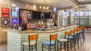 A bar area with a long counter, multiple bar stools, and a variety of bottles and glasses. - Clarion Inn Salt Lake City Airport (Salt Lake City)