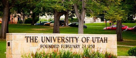 Un cartel de la Universidad de Utah, con una base de piedra y un arreglo floral.