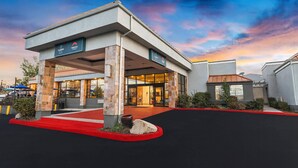 A modern hotel entrance with a red carpet, stone pillars, and a glass facade. - Clarion Inn Salt Lake City Airport (Salt Lake City)