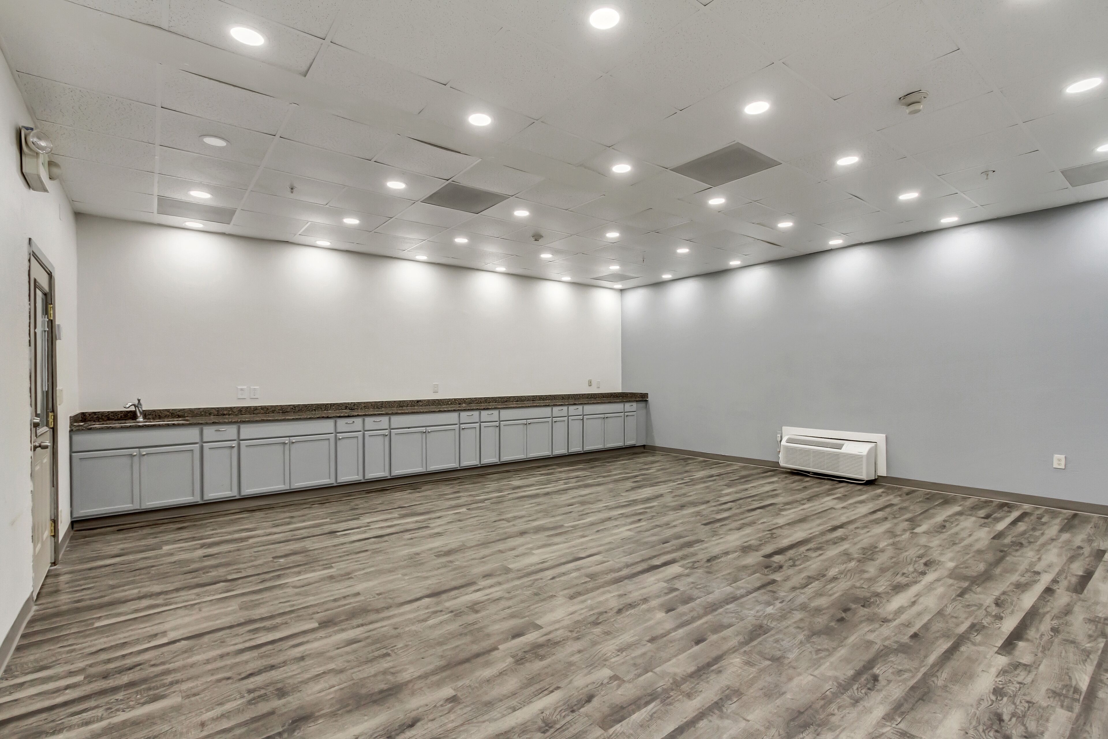 Une pièce spacieuse avec un plancher en bois, des murs blancs et un comptoir de cuisine intégré.