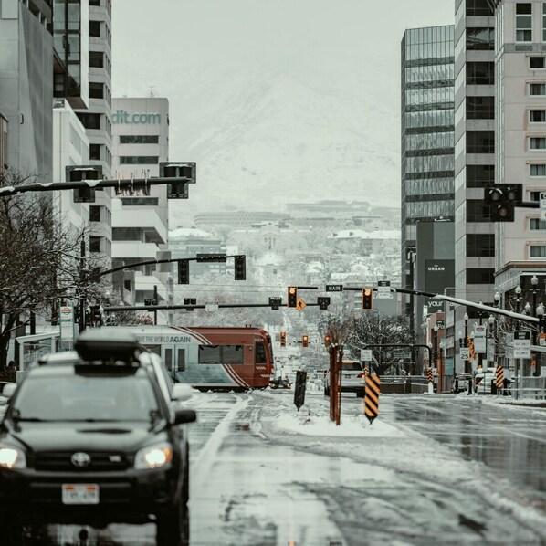 Una calle nevada en la ciudad, con semáforos, un autobús y edificios al fondo.