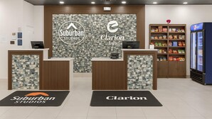 A reception area with two counters labeled 'Suburban Studios' and 'Clarion Inn'. There are vending machines, a refrigerator, and a snack shelf. - Clarion Inn Salt Lake City Airport (Salt Lake City)