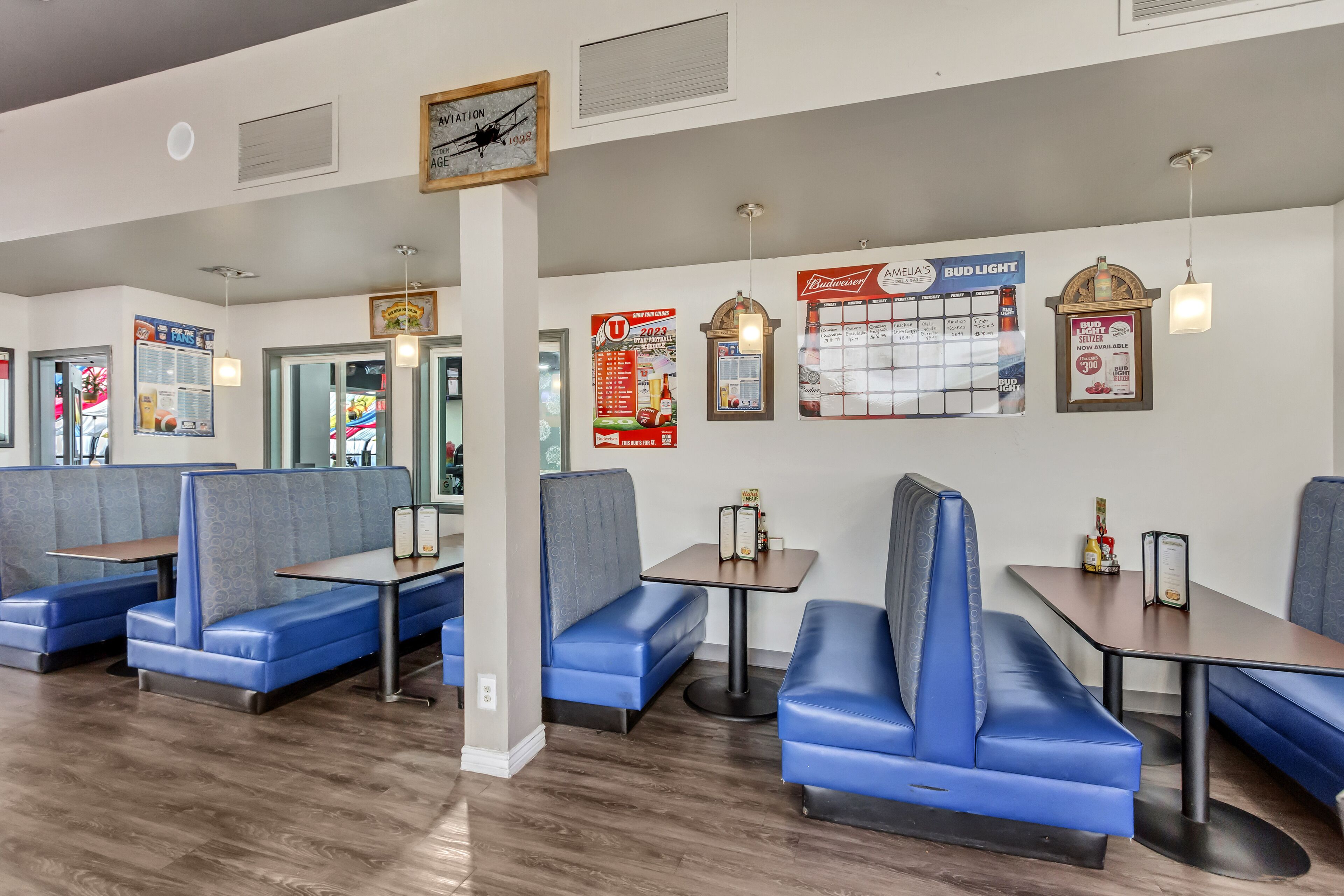 A restaurant with blue booths and tables, wooden flooring, and various posters on the walls.