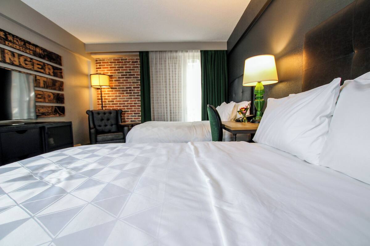 Ein Hotelzimmer mit einem großen Bett, einem Schreibtisch, einem Sessel und einem Fernseher.