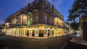 Un hôtel à plusieurs étages, doté d’une façade en briques, de fenêtres en arc de cercle et d’espaces extérieurs aménagés avec des lampes décoratives.