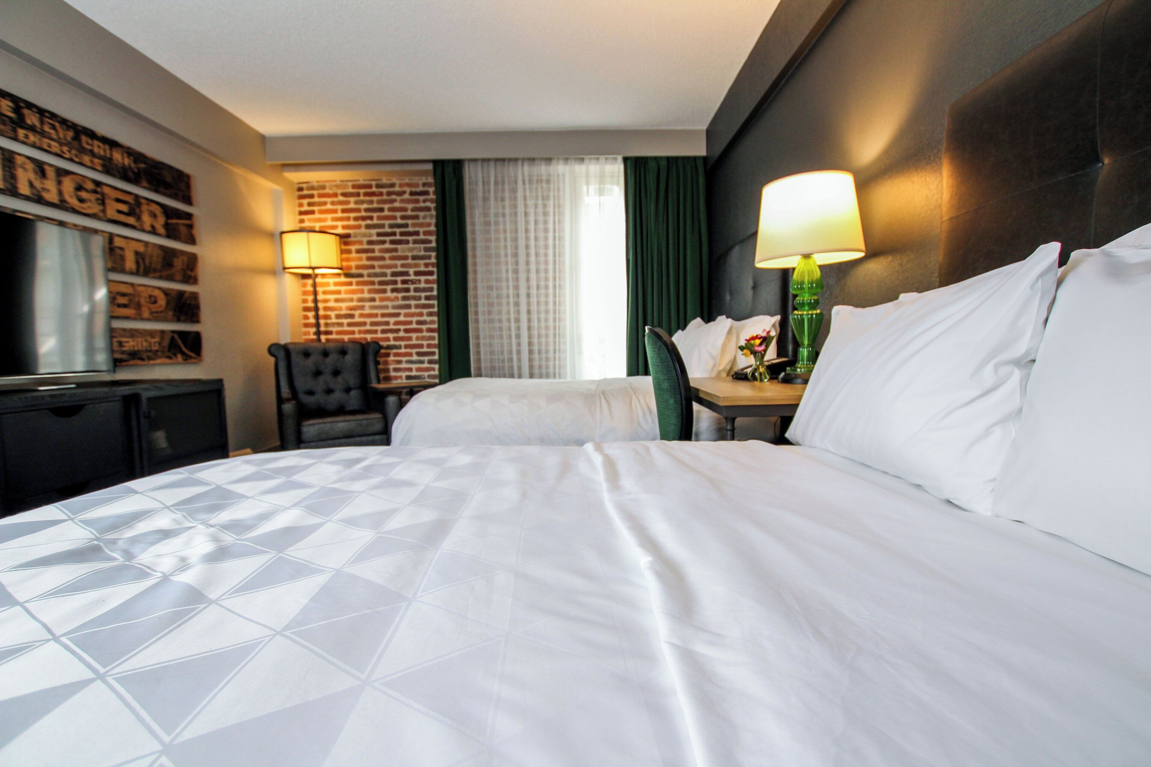 A hotel room with a large bed, a desk, a chair, and a television.