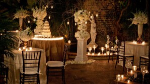 Un lieu de réception en plein air pour les mariages, avec des tables dressées pour le repas, entourées de compositions florales décoratives et de bougies.