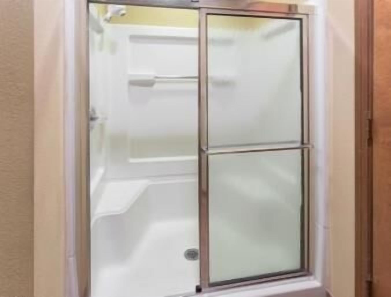 Eine begehbare Duschkabine aus Glas, eine weiße Badewanne und ein weißer Handtuchhalter.