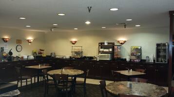 A hotel kitchen with multiple dining tables, a coffee machine, and a microwave.