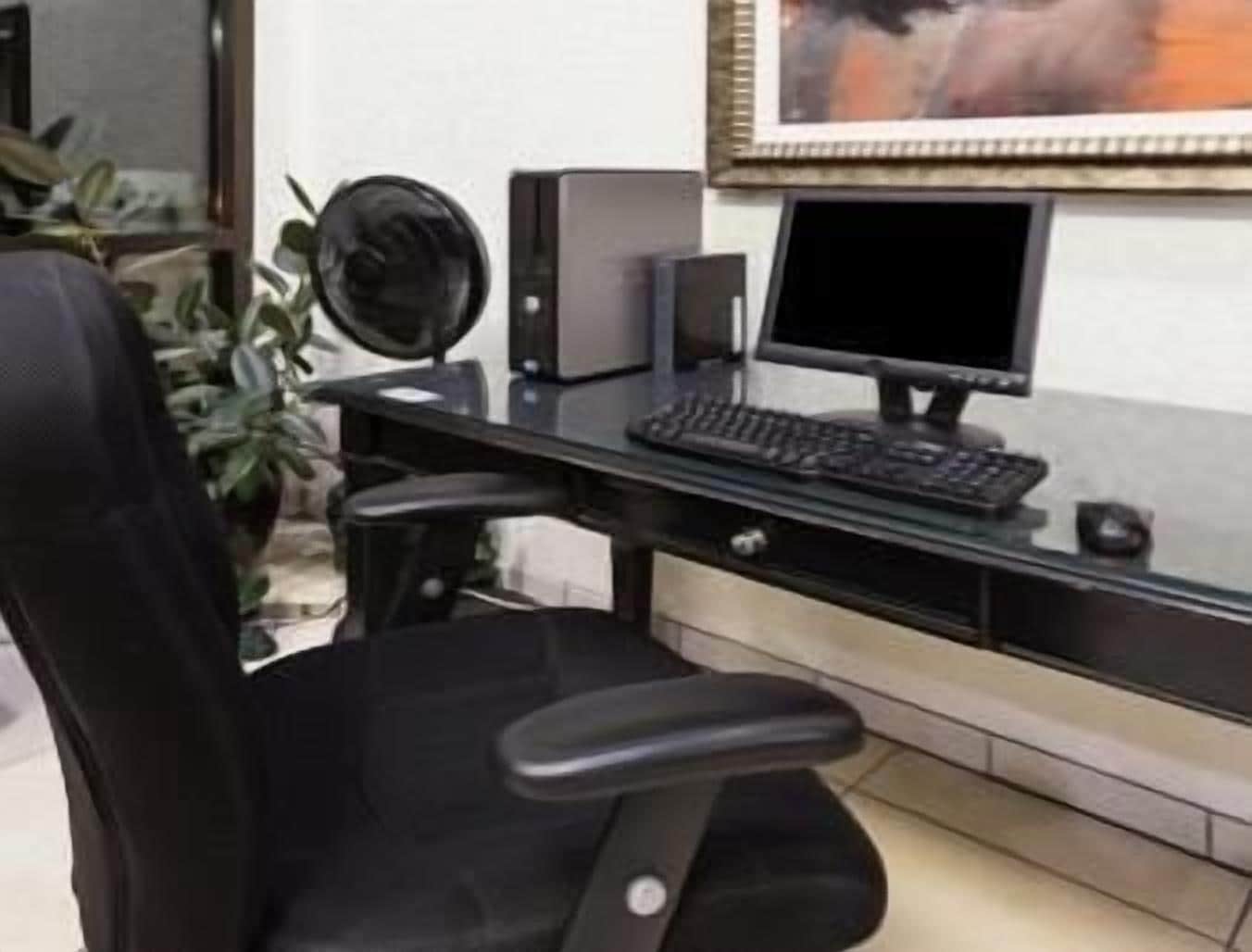 A modern office desk with a computer, keyboard, and speakers.