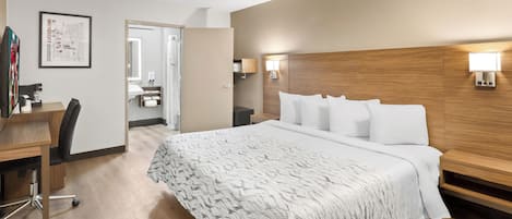 Une chambre d’hôtel avec un grand lit, un bureau avec une chaise, une tête de lit en bois et deux lampes fixées au mur.