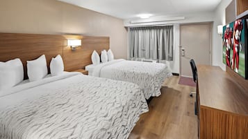 Une chambre d’hôtel avec deux lits, un bureau, une chaise, une télévision et une porte.