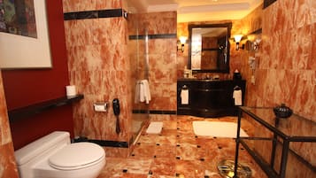 A modern bathroom with a marble floor, a glass shower enclosure, a black vanity, and a white toilet.
