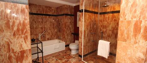 A bathroom with a bathtub, toilet, and glass-enclosed shower area.