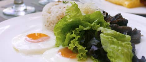 Un plato con huevo frito, arroz, lechuga y carne.