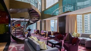 A spacious lobby with a central spiral staircase, comfortable seating areas, and large windows offering city views. - Diamond Hotel Philippines (Manila)