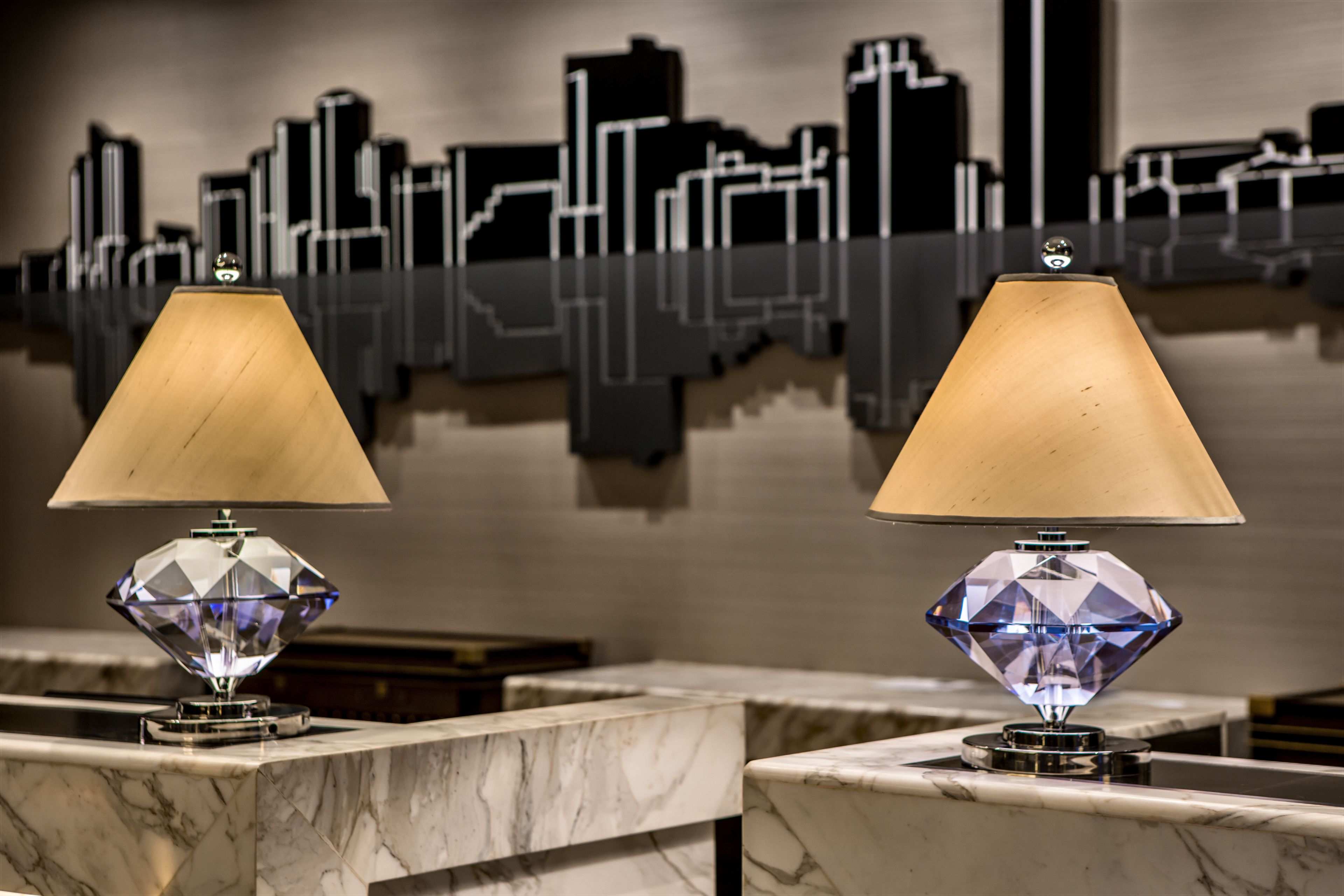 Two crystal lamps on marble countertops with a cityscape mural in the background.