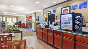 Un espace pour le petit-déjeuner à l’hôtel, avec un comptoir en libre-service, un réfrigérateur et un coin salon.