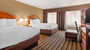 Une chambre d’hôtel avec deux lits, un bureau, une chaise et un téléviseur.