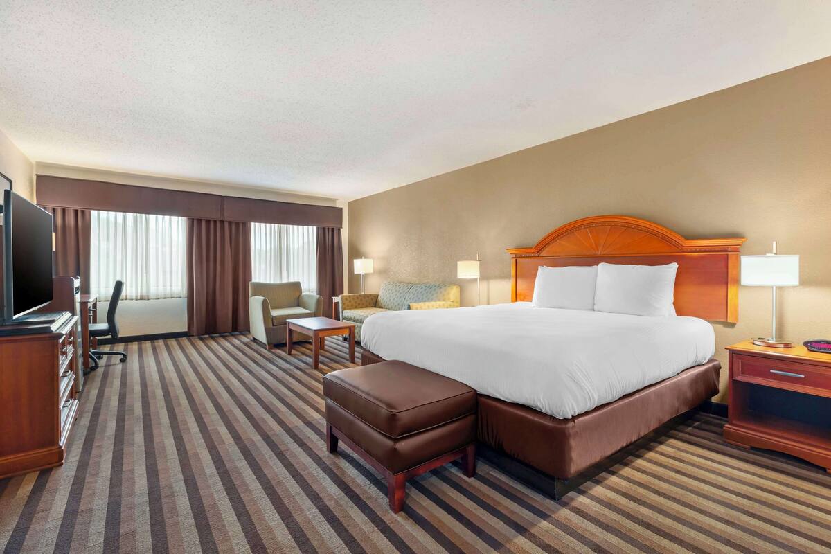 A hotel room with a large bed, a TV, a desk, and a chair.