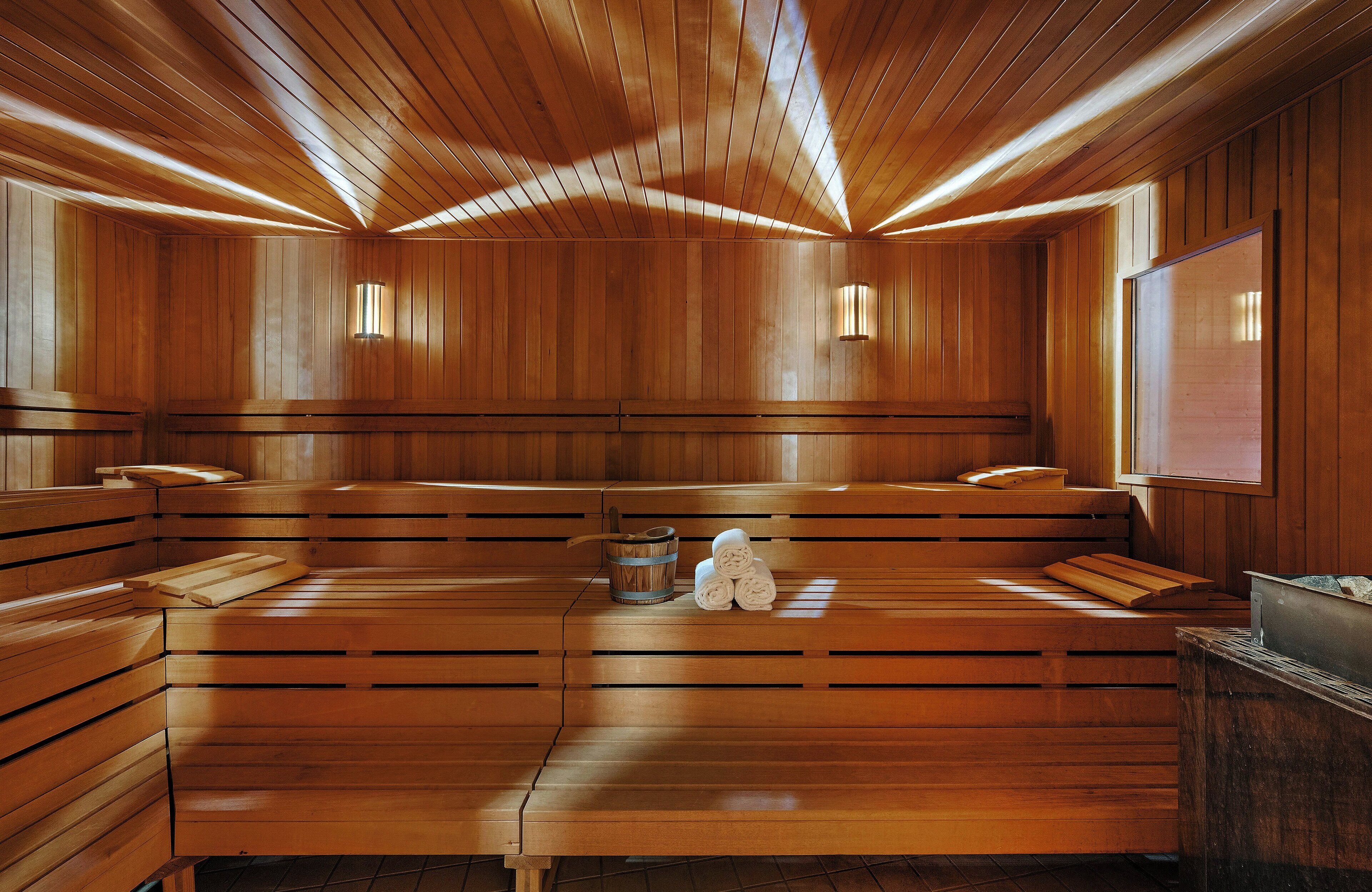 A sauna with wooden benches, a bucket, and towels.
