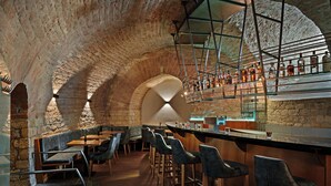 A bar area with stone arches, wooden bar stools, and a variety of bottles on shelves. - Leonardo Hotel Mainz (Mainz)