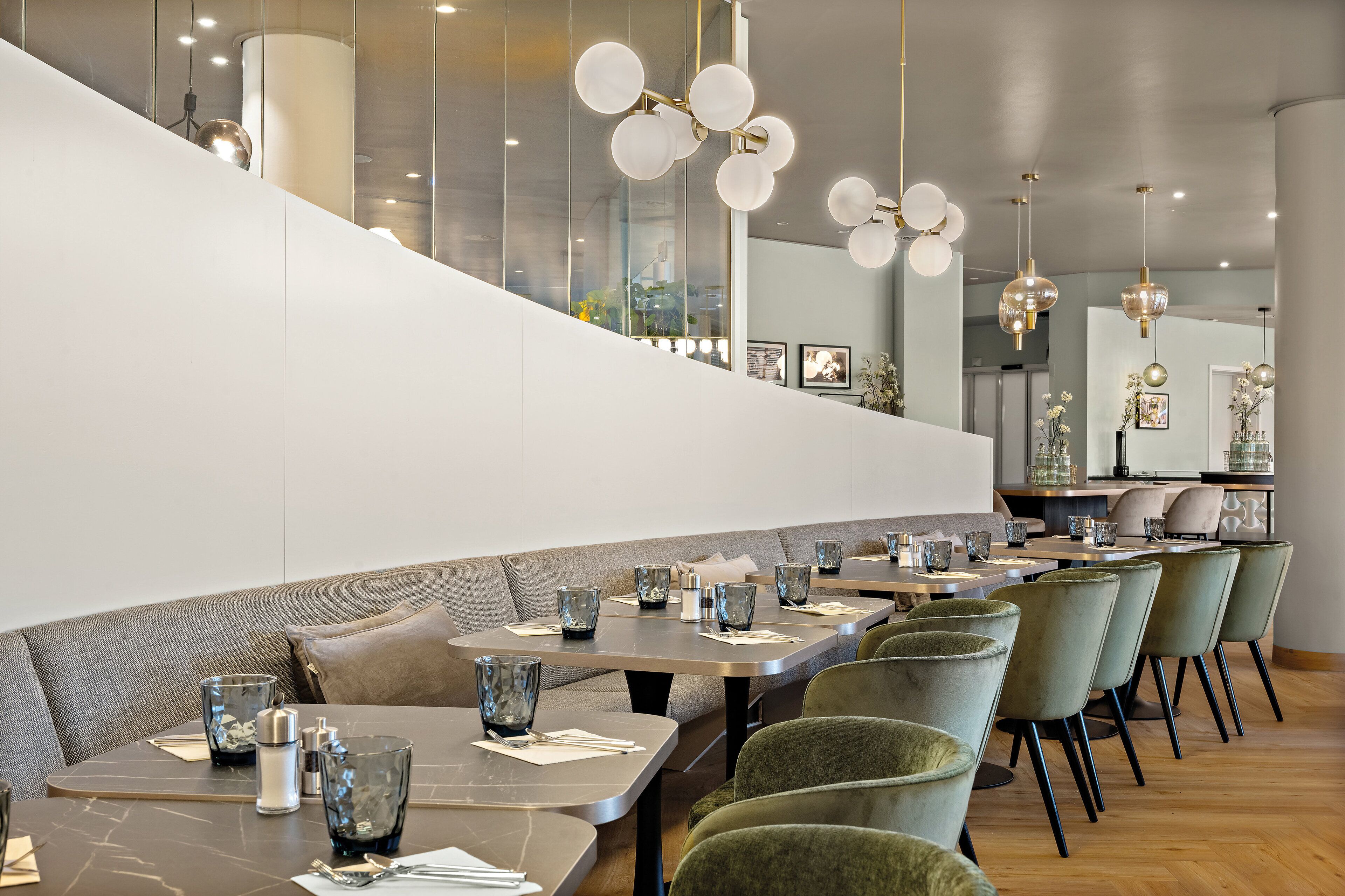 Ein modernes Restaurant mit einer langen Theke, gepolsterten Sitzmöglichkeiten und Pendelleuchten.
