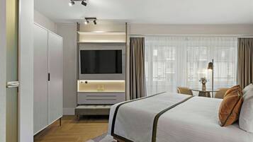 Una habitación de hotel moderna con una cama, un televisor, un escritorio y una ventana con cortinas.