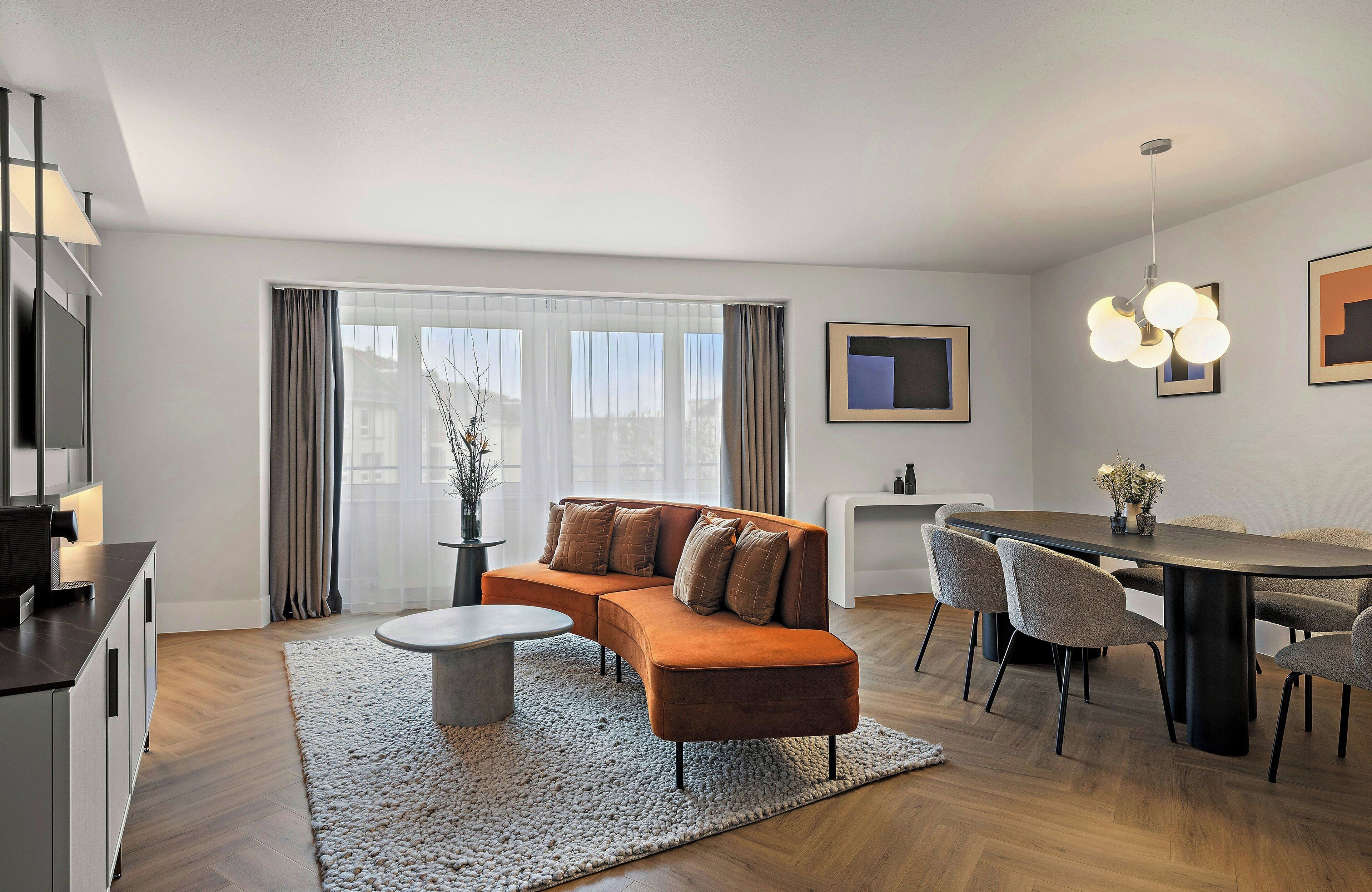 A modern living room with a sectional sofa, dining table, and chairs.