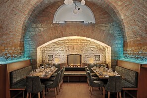 A restaurant with a brick interior, wooden tables, and cushioned seating. - Leonardo Hotel Mainz (Mainz)