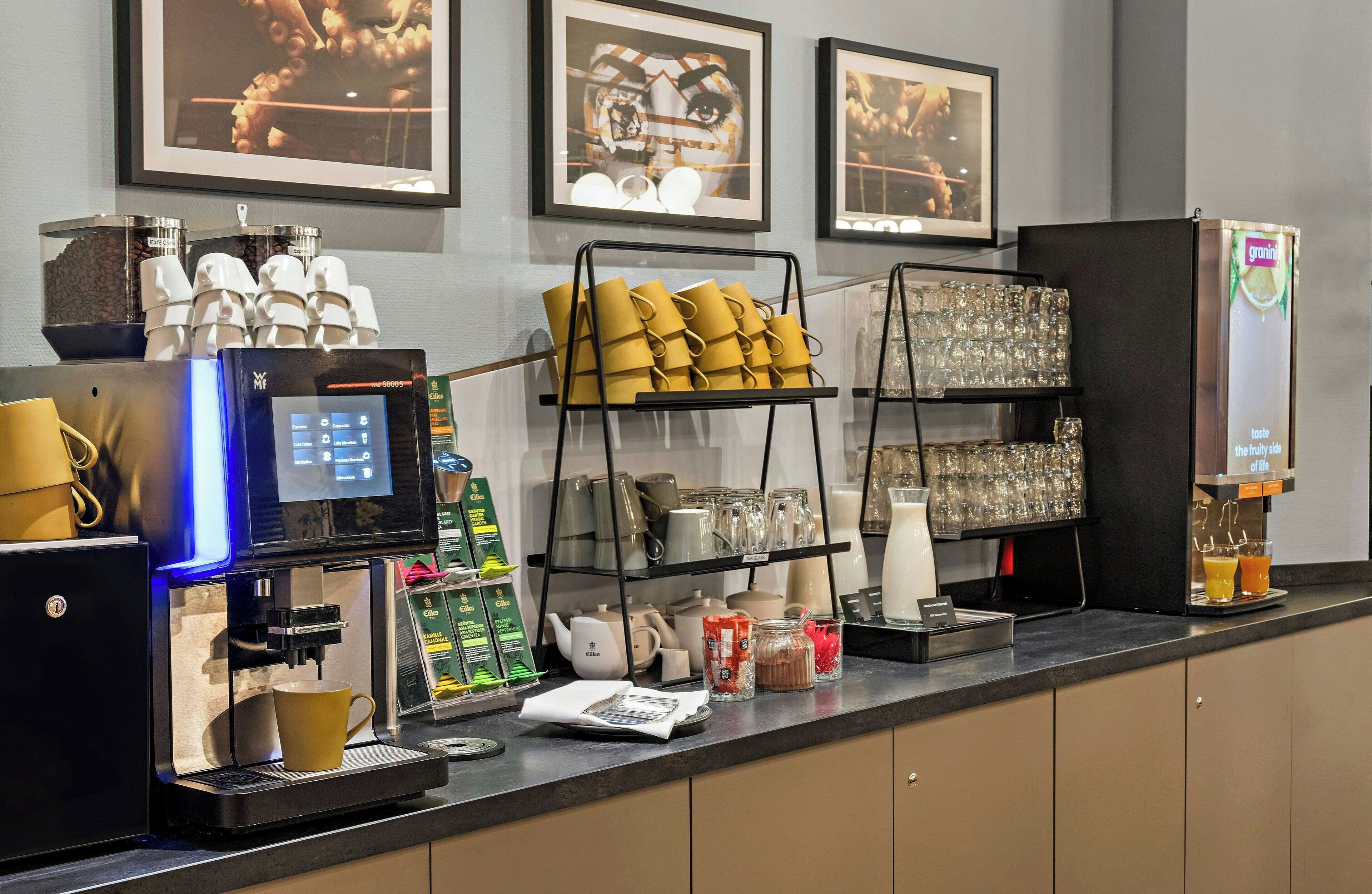Una estación de café con una máquina de café, tazas y una exhibición de granos de café.