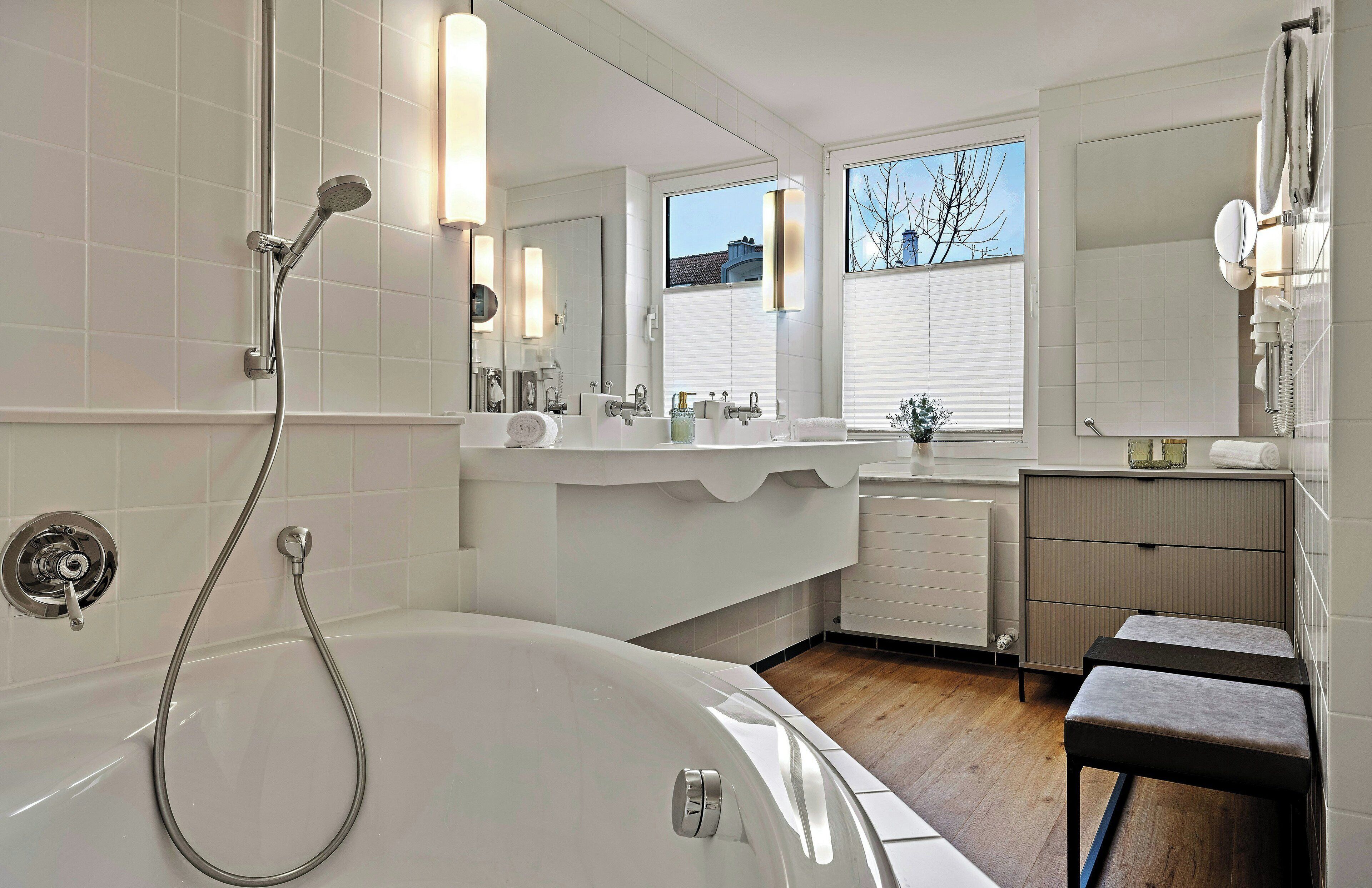 Un baño moderno con bañera, ducha, tocador con espejo y ventana.