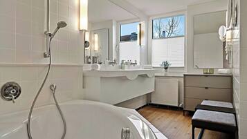 Un baño moderno con bañera, ducha, tocador con espejo y ventana.