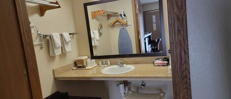A bathroom with a sink, mirror, towel rack, and a bench.