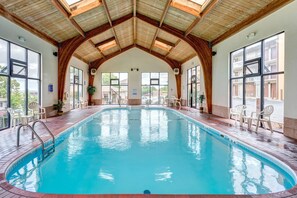 An indoor swimming pool with a wooden ceiling and large windows.
