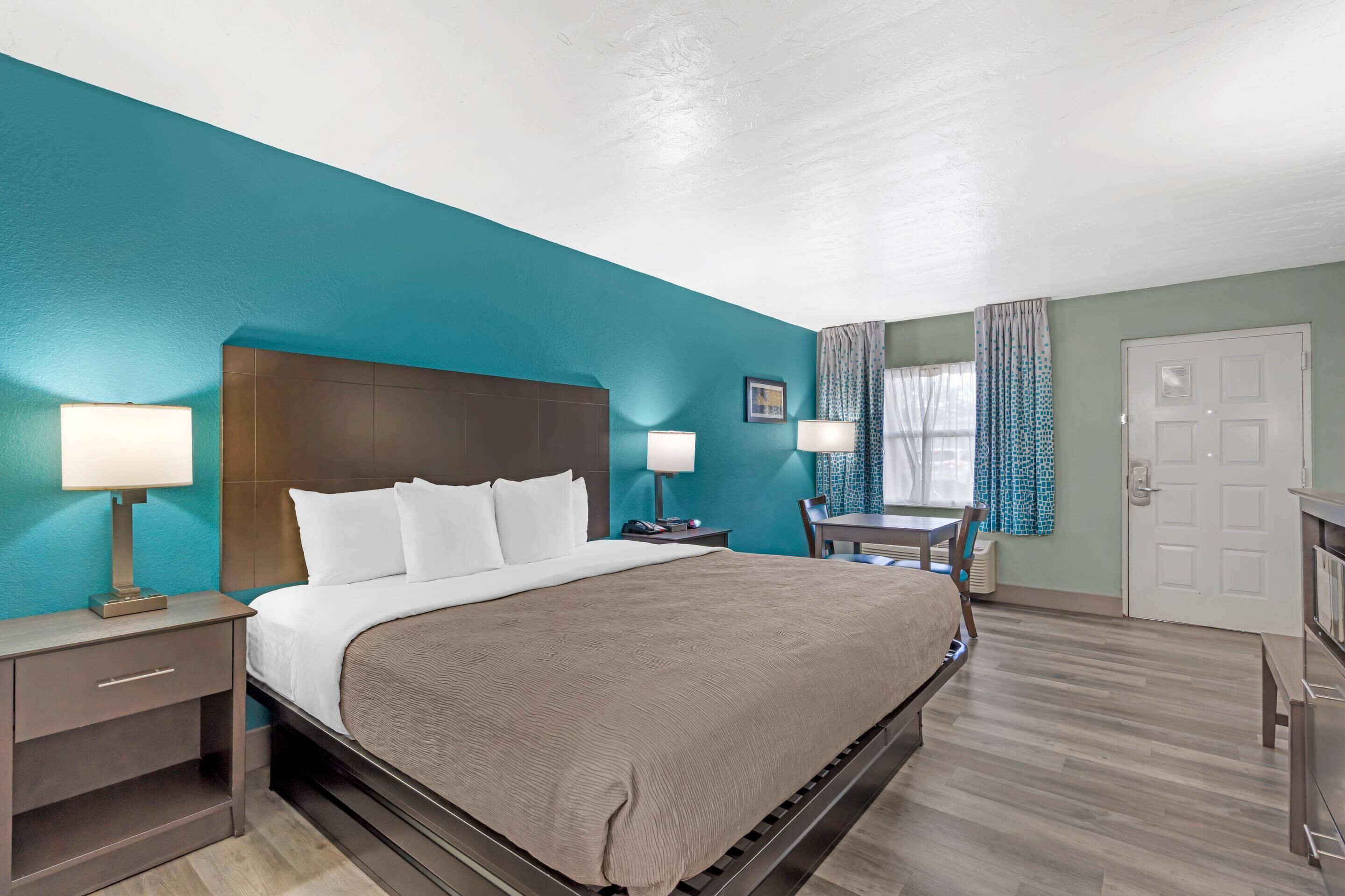 Habitación de hotel con una cama grande, dos mesitas de noche con lámparas, un escritorio y una silla.
