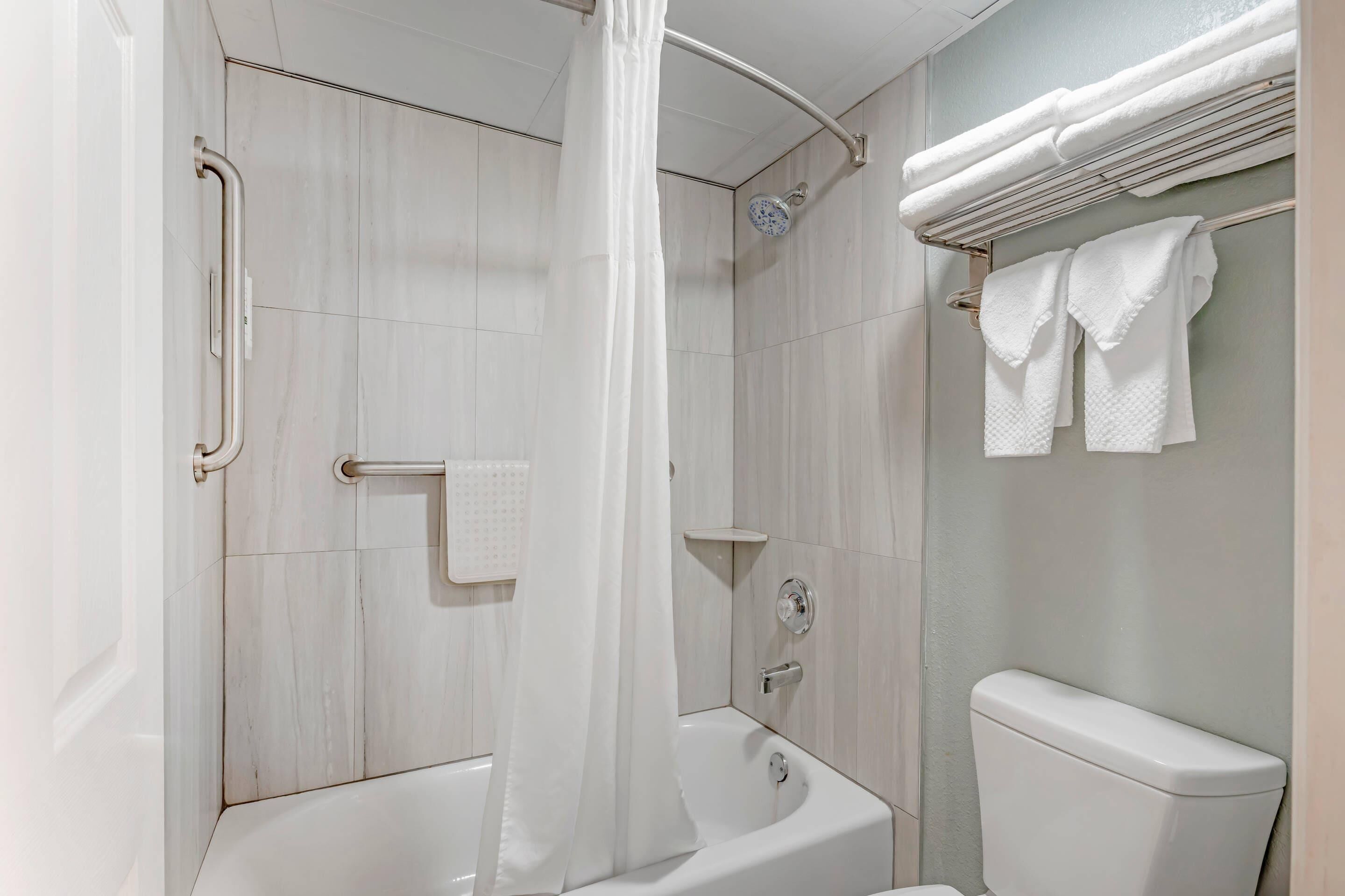 A bathroom with a shower, a bathtub, and a toilet.